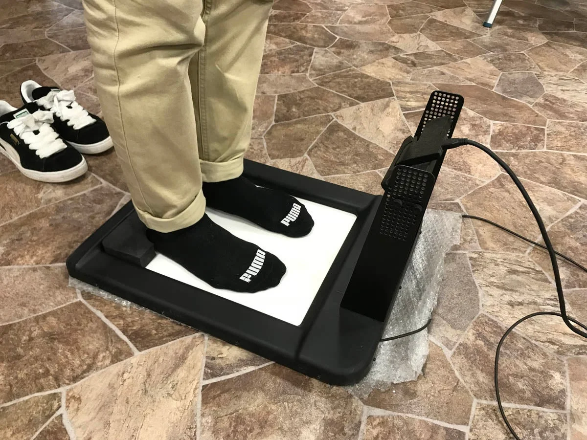 プーマの靴下を履いた人物が足の測定器の上に立っている様子