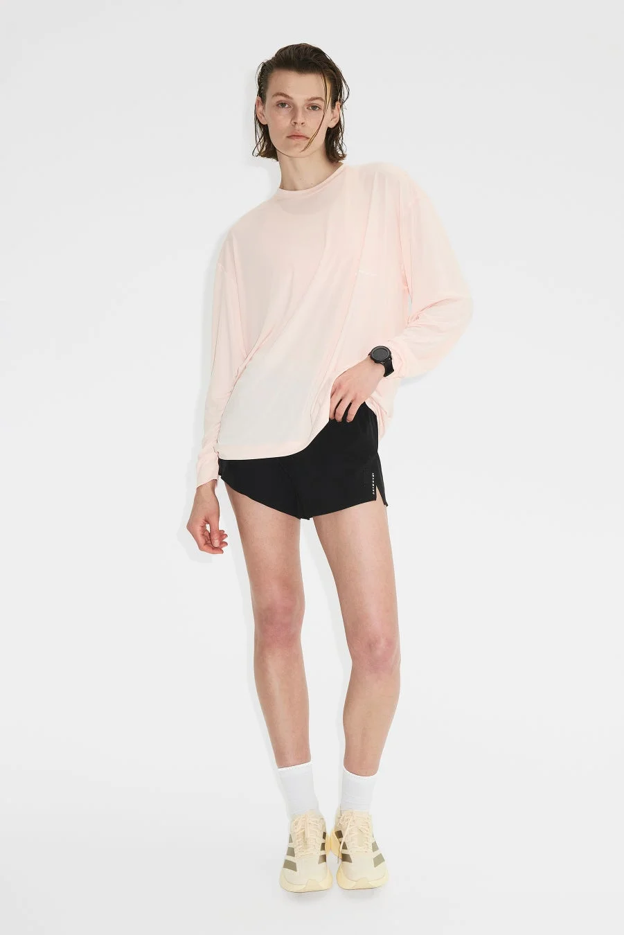 ピンクの長袖Tシャツと黒いショートパンツを着用した男性モデル