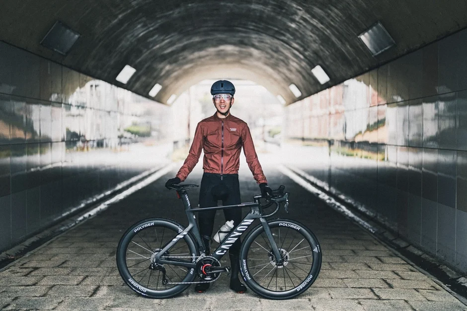 サイクリングウェアを着た男性が、ロードバイクと共にトンネルの中で立っています。