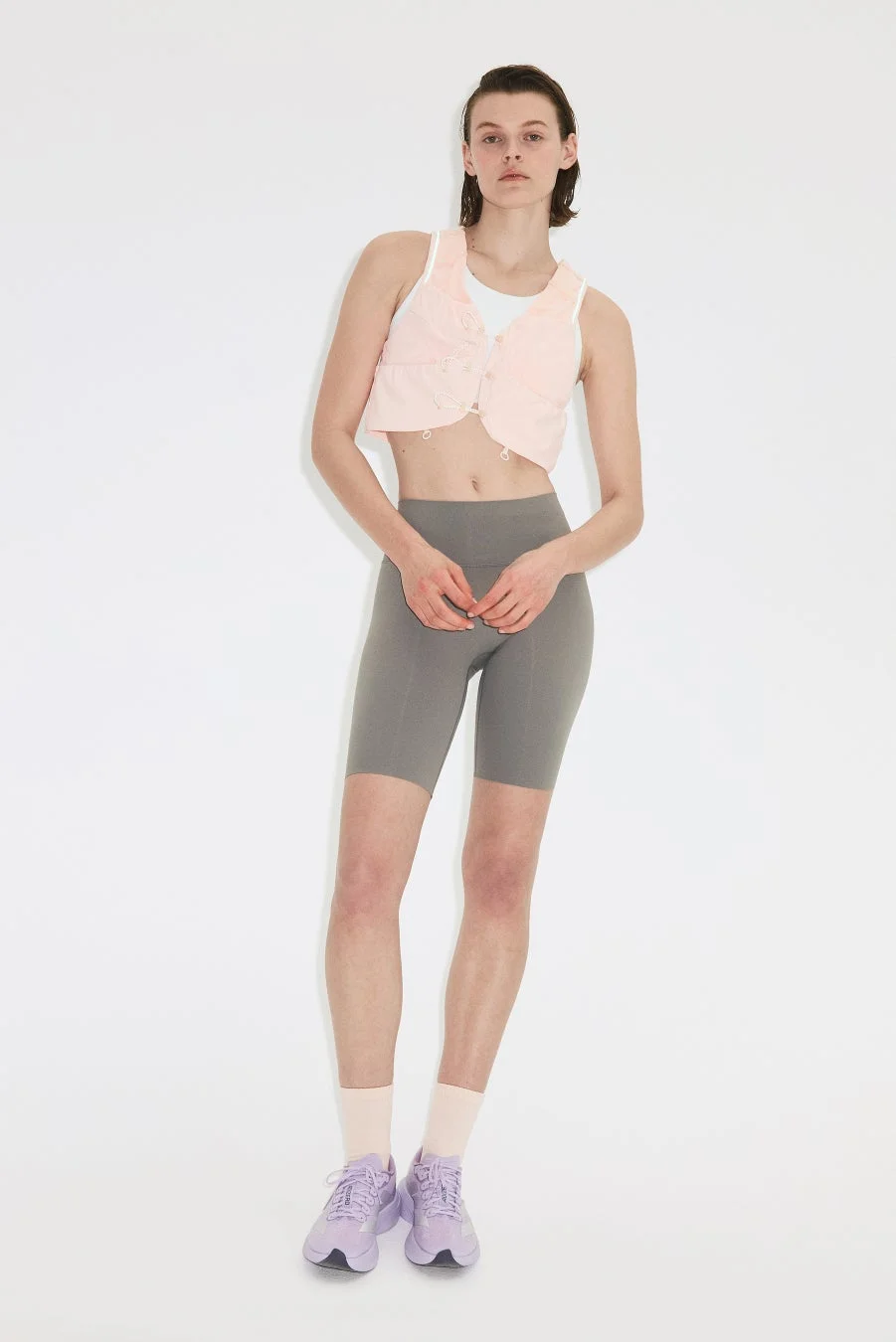 ピンクのクロップドベストとグレーのサイクリングショーツを着用した女性モデル