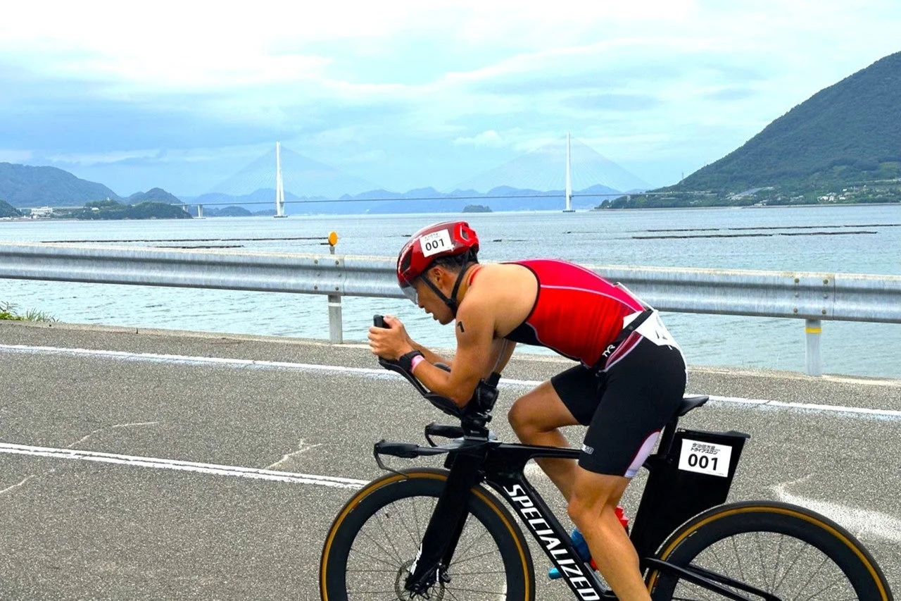 海沿いの道をタイムトライアルバイクで走行するアスリート