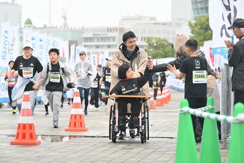 車椅子ランナーとハイタッチする人々