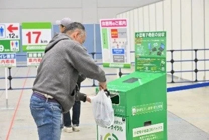 小型電子機器の回収ボックスに白い袋に入った物を入れている男性