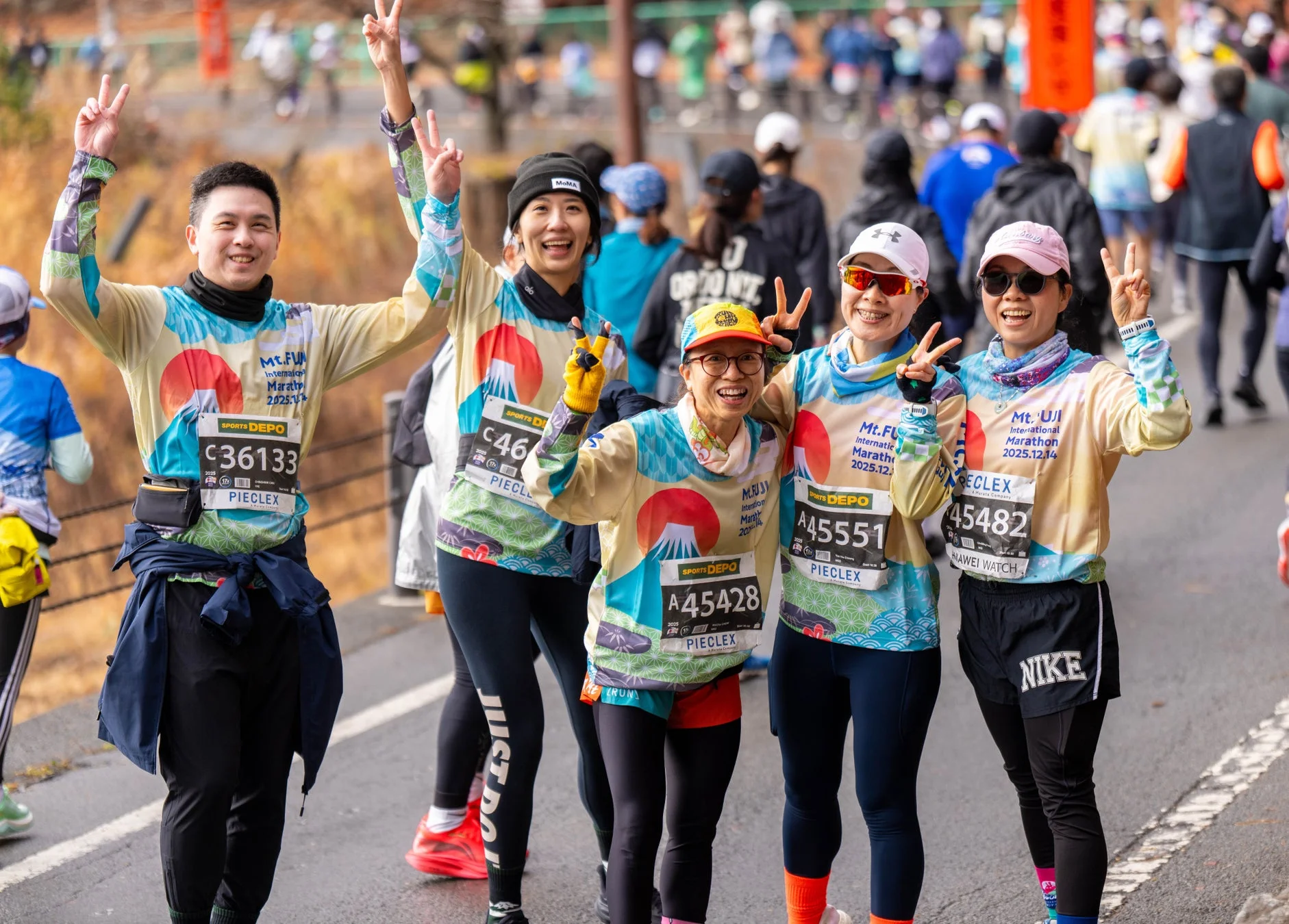富士山国際マラソンに参加しているランナーたちが、笑顔でピースサインをしながらポーズをとっている様子