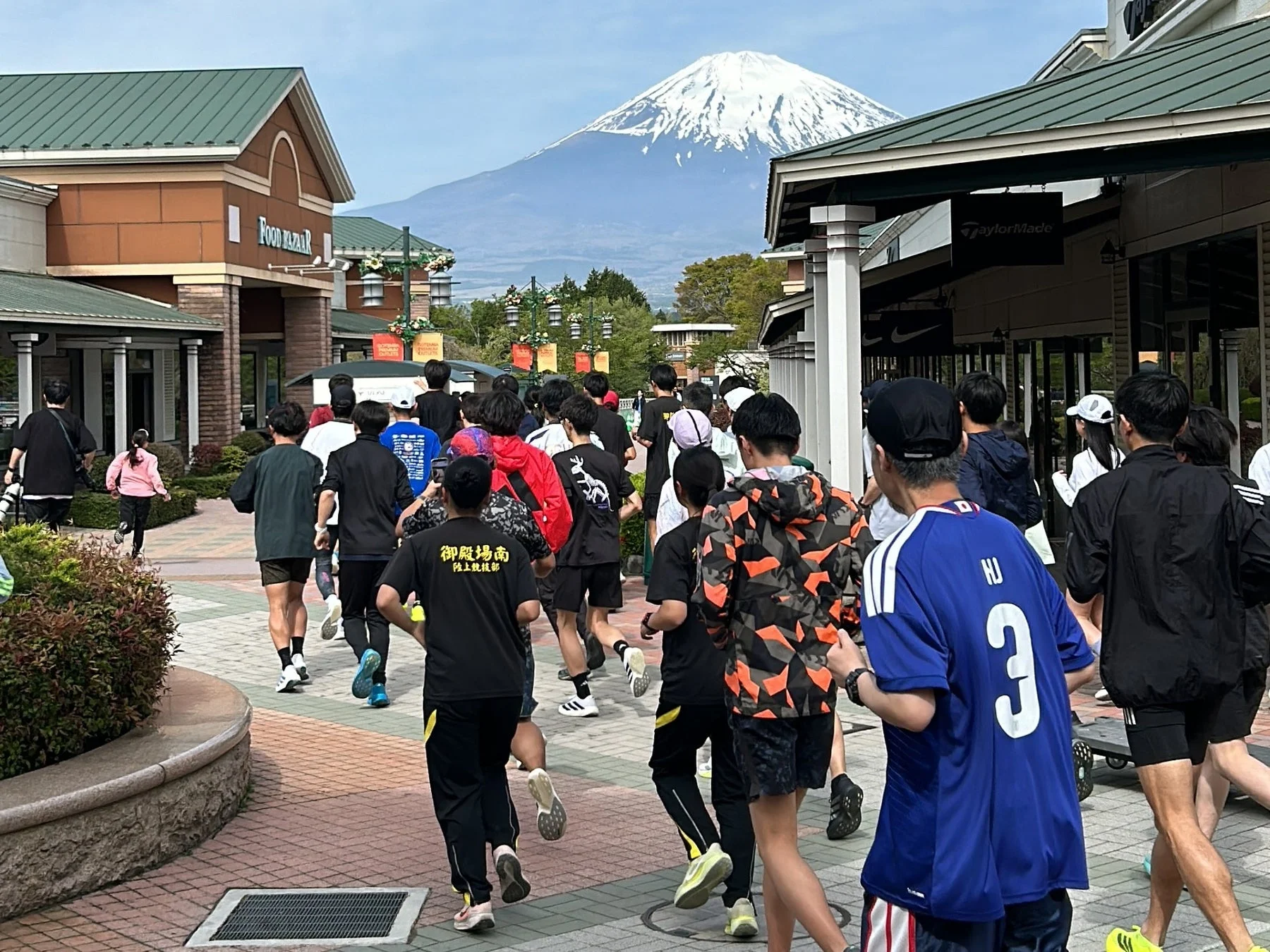 富士山を背景にアウトレットモールを行き交う人々