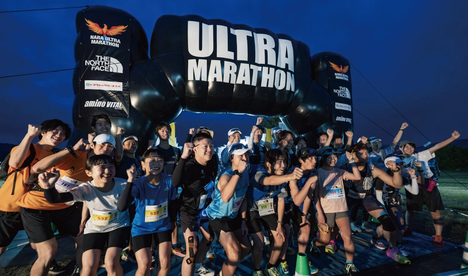 「NARA ULTRA MARATHON」のアーチの下で拳を突き上げるランナー